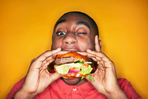Mastigar pouco: foto colorida de jovem engolindo hamburguer