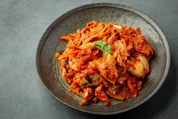 Kimchi pronto para consumo em prato preto. Metrópoles
