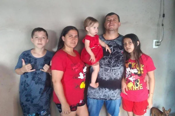 Na foto vemos uma familia com um meino, uma mulher, um homem com uma menina bebe de colo e outra menina, já grande