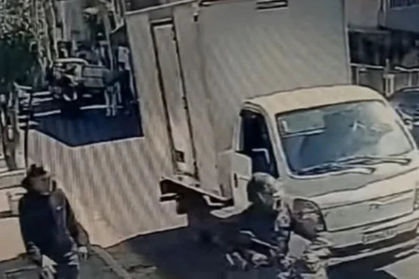 Imagem colorida de câmera de segurança mostrando um caminhão, um moto ao lado, e um homem de blusa preta. Metrópoles