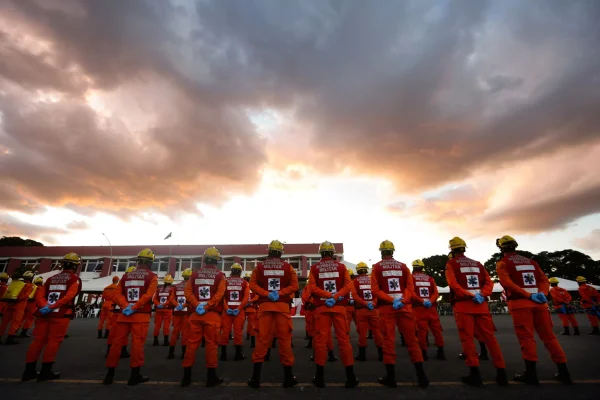 Imagem colorida de militares do Corpo de Bombeiros do DF. Ao fundo, o pôr-do-sol