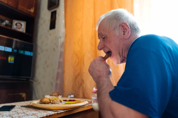 Foto mostra Idoso comendo sozinho na sala de casa alimentação nutrição terceira idade - Metrópoles