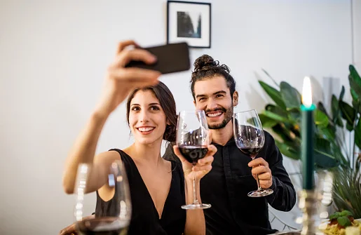casal segurando celular e garrafa de vinho