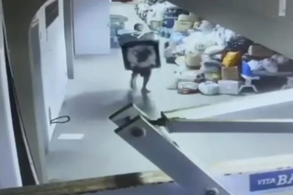Homem carrega máquina de lavar nas mãos dentro de ginásio - Metrópoles