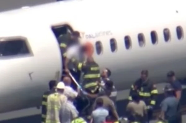 Imagem colorida mostra piloto que passou mal saindo de avião com ajuda de bombeiros - Metrópoles