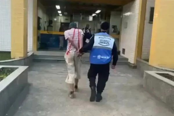 Foto colorida: print de um vídeo no qual um homem fantasiado de chaves é detido por agentes de segurança por porte de maconha