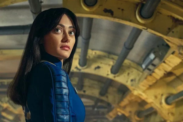 Moça olhando para o horizonte com roupa azul na série Fallout - Metrópoles