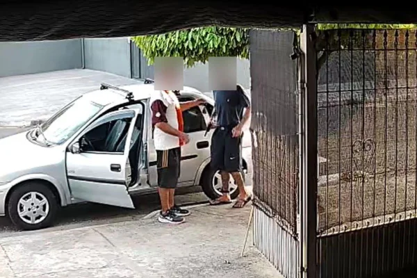 Imagem colorida mostra homem com tornozeleira rendendo motorista de carro com arma na frente de casa - Metrópoles