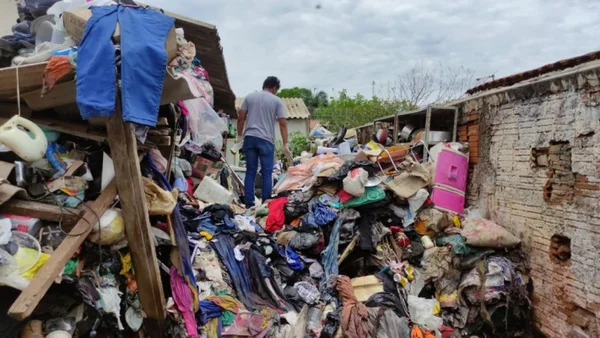Homem em cima de lixo acumulado em quintal de casa - Metrópoles