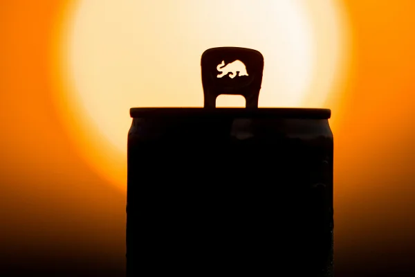 Foto colorida com alto contraste de lata de bebida energética com fundo amarelo e laranja - Metrópoles.