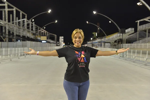 Imagem colorida mostra a locutora Eloise Matos, a nova voz das notas do Carnaval de São Paulo; ela é uma mulher loira. de cabelos curtos, pele morena, vestindo uma camiseta preta e calça jeans - Metrópoles