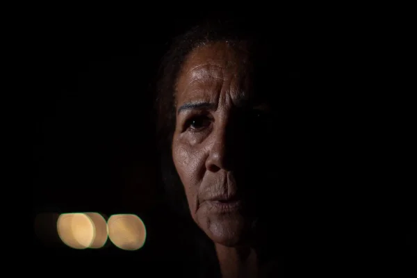 Imagem mostra o rosto de uma mulher. Ela está no escuro, com a metade da face iluminada - Metrópoles