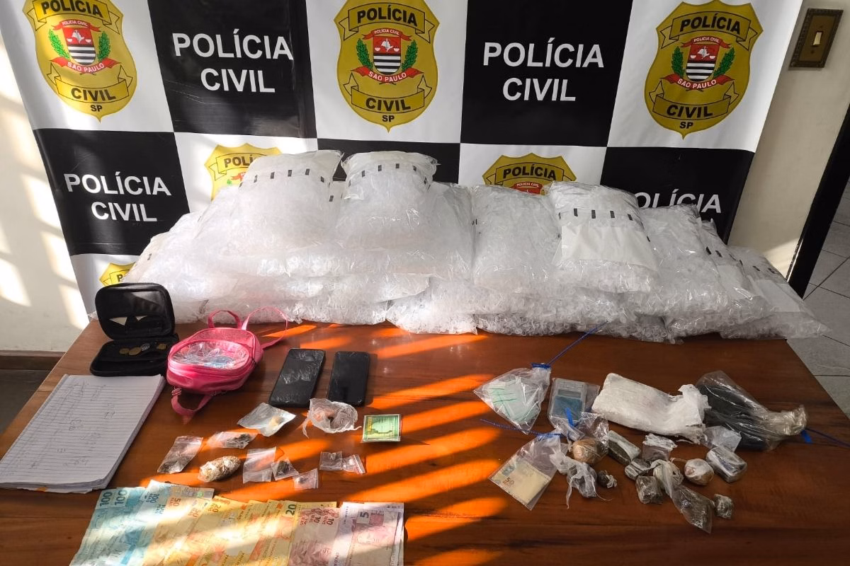 Imagem colorida mostra dinheiro, drogas e outros materiais apreendidos em operação contra o tráfico. Metrópoles