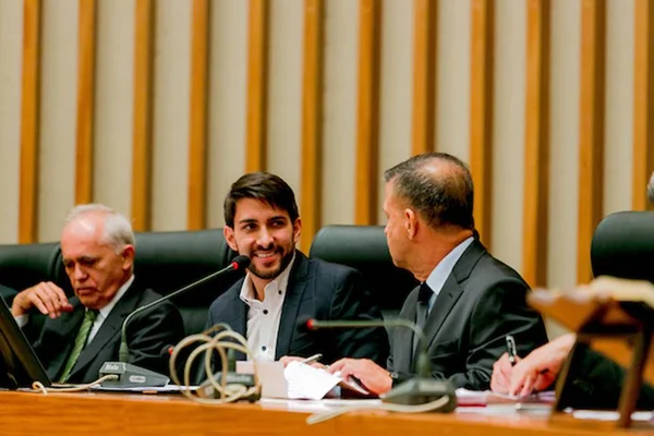 O deputado distrital Cristiano Araújo durante sessão no plenário da Câmara Legislativa do DF. Ele está sentado na mesa da presidência e sorri - Metrópoles