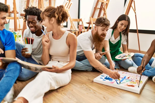 Foto colorida de um grupos de jovens adultos fazendo trabalhos artísticos