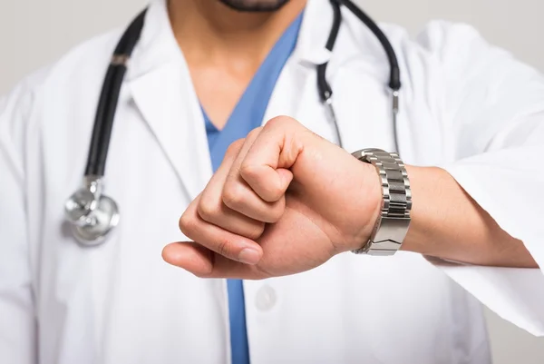 Foto mostra médico olhando relógio. Avaliando tempo, sintomas