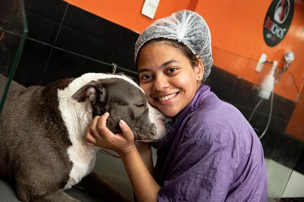 Foto colorida de uma mulher em um petshop com um cachorro - Metrópoles