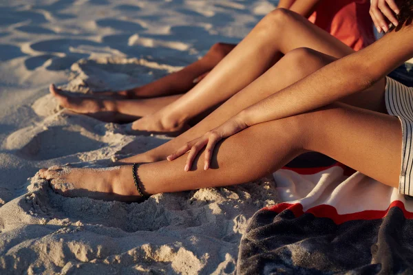 Foto colorida de pessoas pegando sol na praia - Bronzeamento natural: entenda riscos e cuidados da exposição ao sol