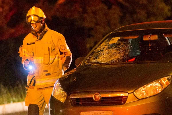 Bombeiro ao lado de carro com vidro quebrado