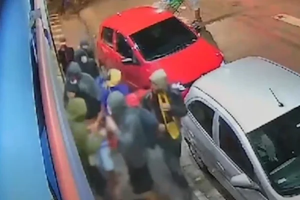Imagem colorida de homens encapuzados invadindo mercado. Metrópoles