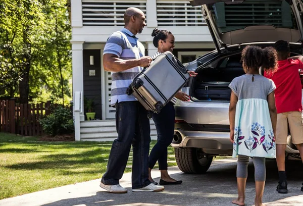 Família colocando malas dentro do carro para viajar
