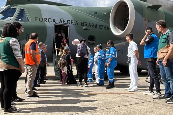 Imagem colorida mostra duas fileiras de pessoas ao lado da porta de saída de aeronave da Força Aérea Brasileira. As pessoas esperam desembarque de passageiros - Metrópoles
