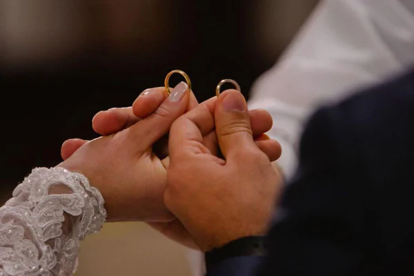 Casal segurando alianças de casamento durante cerimônia