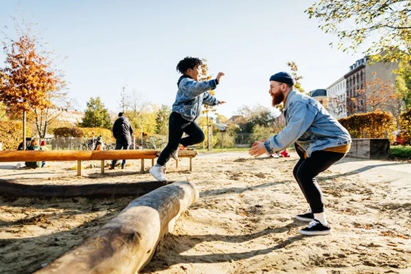 Adulto brincando com criança em um parque - Metrópoles