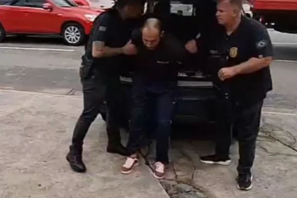 Imagem colorida de homem preso chegando no Deic. Metrópoles