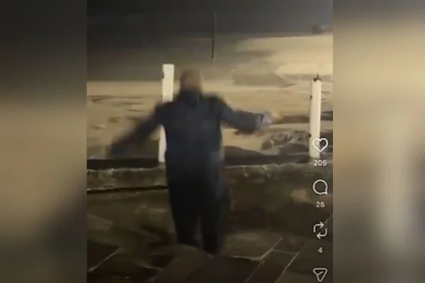 Foto colorida de vídeo em que GCM é "engolido" por cratera no litoral de São Paulo.