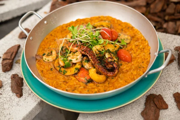 na foto temos uma panelinha de aluminio com arroz em creme alaranjado e frutos do mar