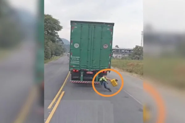 Imagem colorida de homem pendurado no caminhão