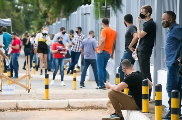 Pessoas em fila em frente a portão