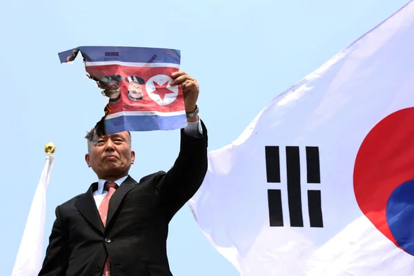 Foto colorida de manifestante sul-coreano rasgando a bandeira da Coreia do Norte - Metrópoles