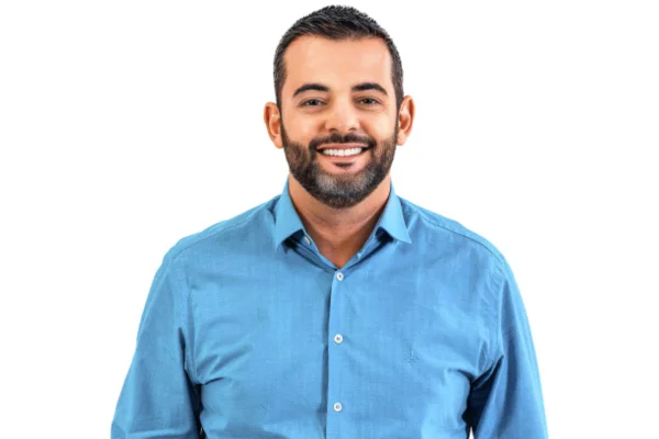 Gustavo Martinelli é um homem adulto branco com cabelos pretos. Na imagem ele usa camisa jeans azul e barba