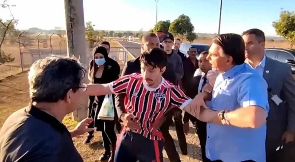 foto colorida de homem sendo segurado por bolsonaro