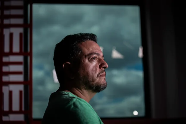 Imagem colorida de um homem com camiseta verde olhado de lado - Metrópoles