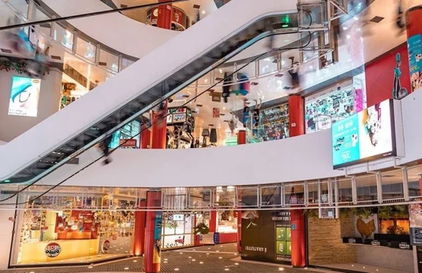 Imagem colorida mostra saguão de shopping com escada rolante - Metrópoles