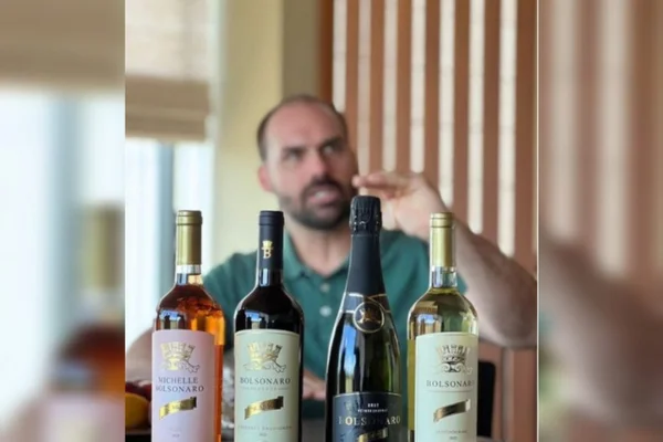 O deputado Eduardo Bolsonaro posa para foto junto as garrafas de vinho do rótulo Bolsonaro