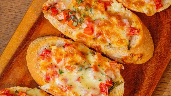 Foto colorida de pizza de pão com recheio de queijo e legumes