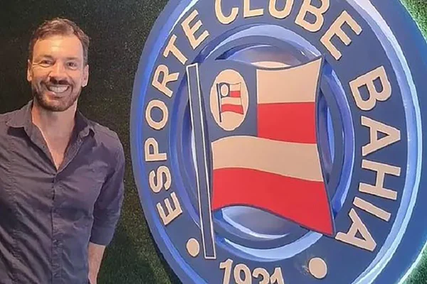 Imagem colorida de Emerson Ferretti ao lado do escudo do Bahia - Metrópoles